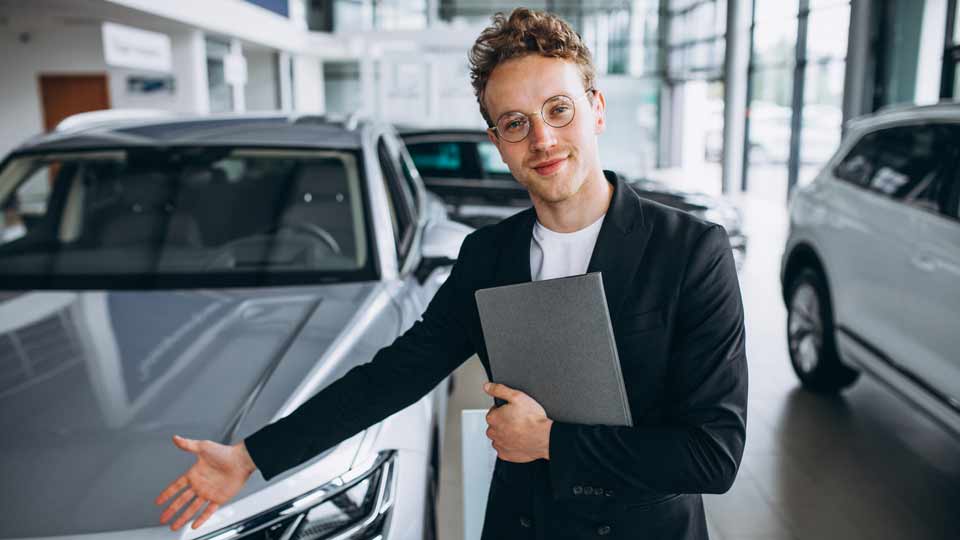 Ein Verkäufer zeigt auf ein Auto und erklärt dem Kunden die Konditionen beim Auto verkaufen Amberg